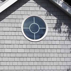 beach house with gray cedar shake siding and round window